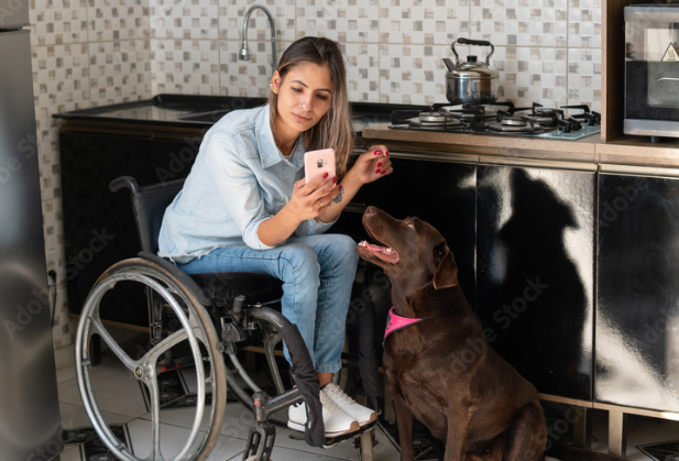 woman in wheelchair with dog beside her