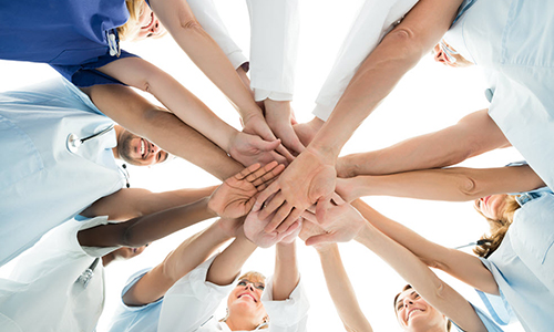 employees in a circle clasping hands